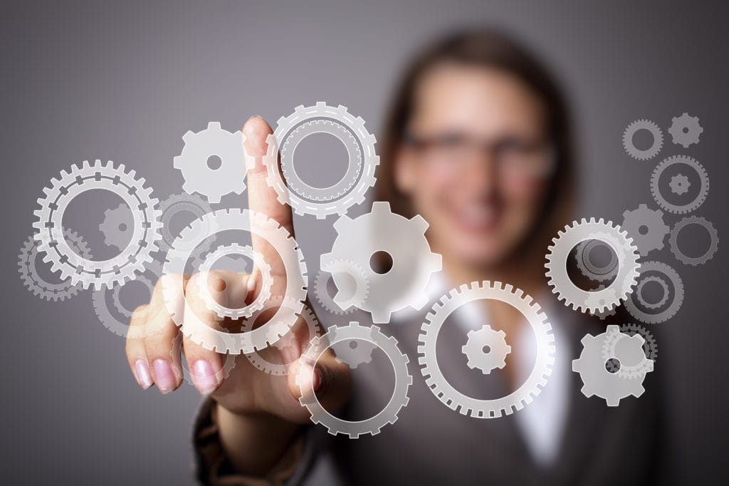 A professional in a blurred background pointing to a set of gears to illustrate health care automation