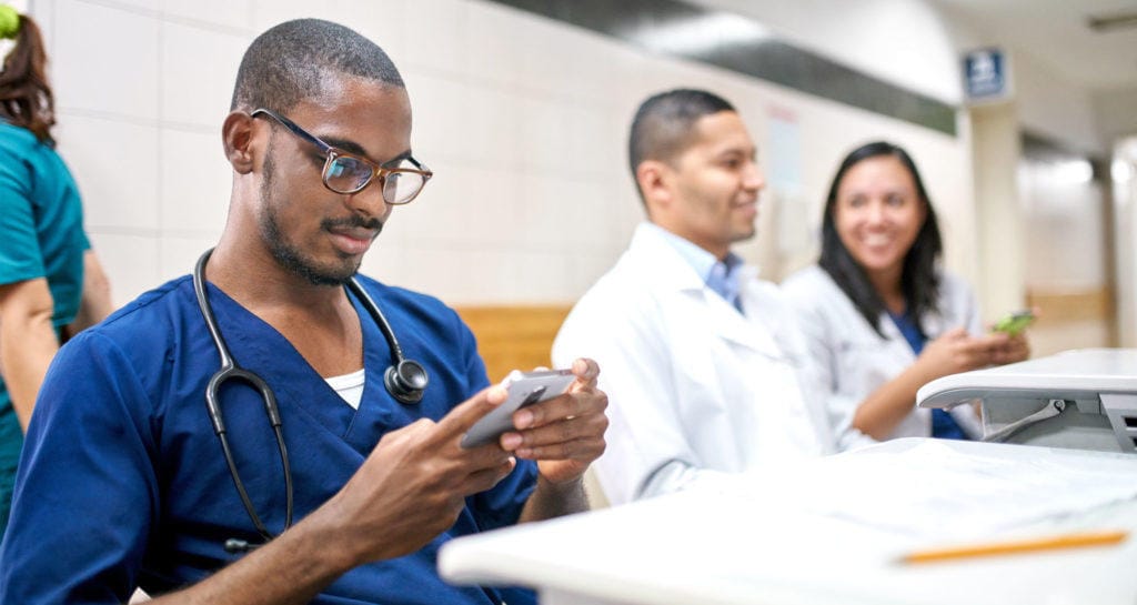 Young physician looking at mobile device representing medical directorship contracts