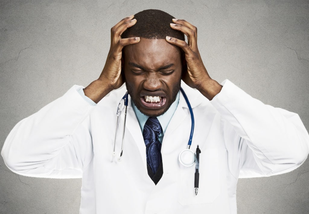 Frustrated doctor holding his head and making a pained expression