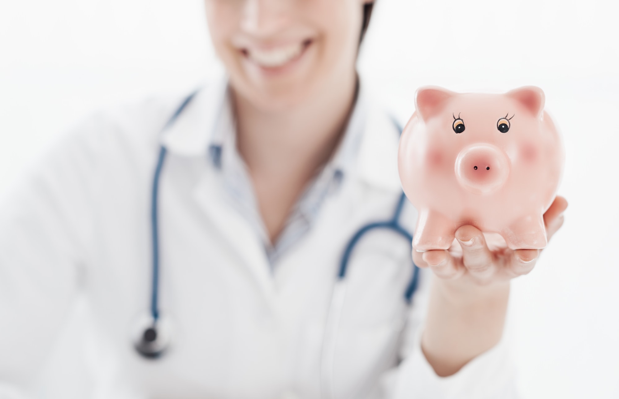 Smiling female doctor holding a piggy bank: health insurance and medical expenses concept