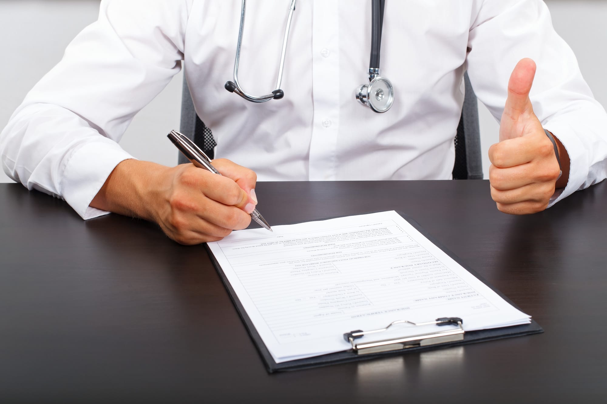 Picture of a doctor's hand signing on the medical report