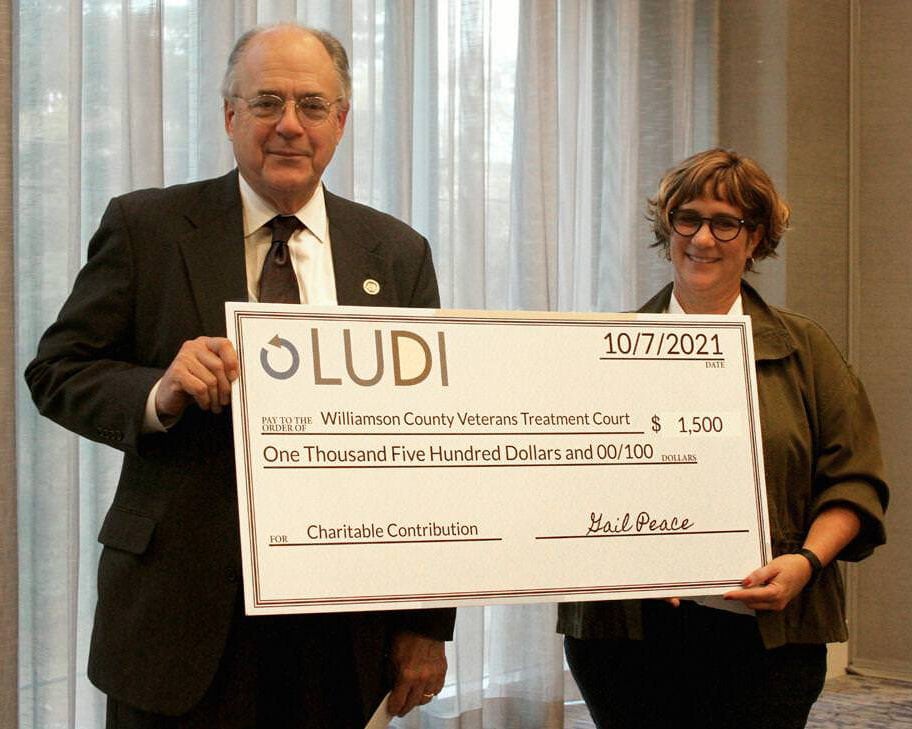 Ludi, Inc. founder and CEO Gail Peace presents Veterans Treatment Court Judge Tom Taylor with a check for $1,500.