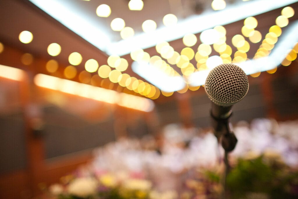 A microphone in focus in a conference room with a background blur and bokeh lights