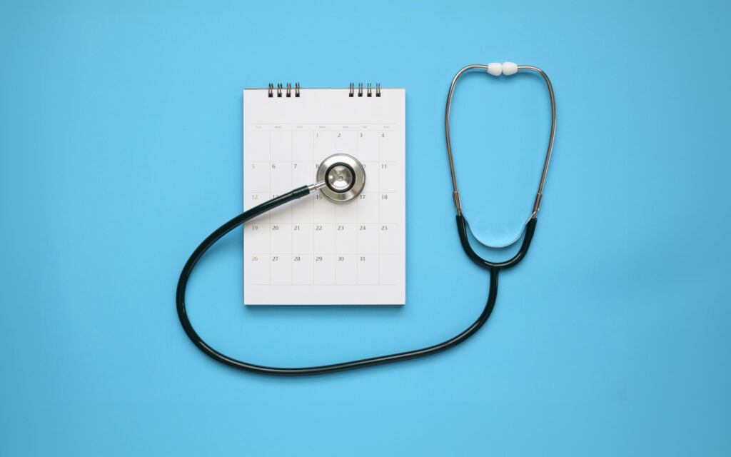 Medical concept featuring a stethoscope and placed on a calendar against an aqua blue background