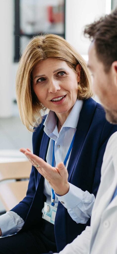 A female compensation expert discusses payments with a physician in a hospital setting