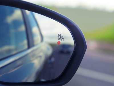 Blind Spot Monitoring system warning light icon in side view mirror of a modern vehicle.